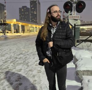 A picture of Membership Officer Gaia Noseworthy standing in a winter photo of the University of Waterloo Bus Station.